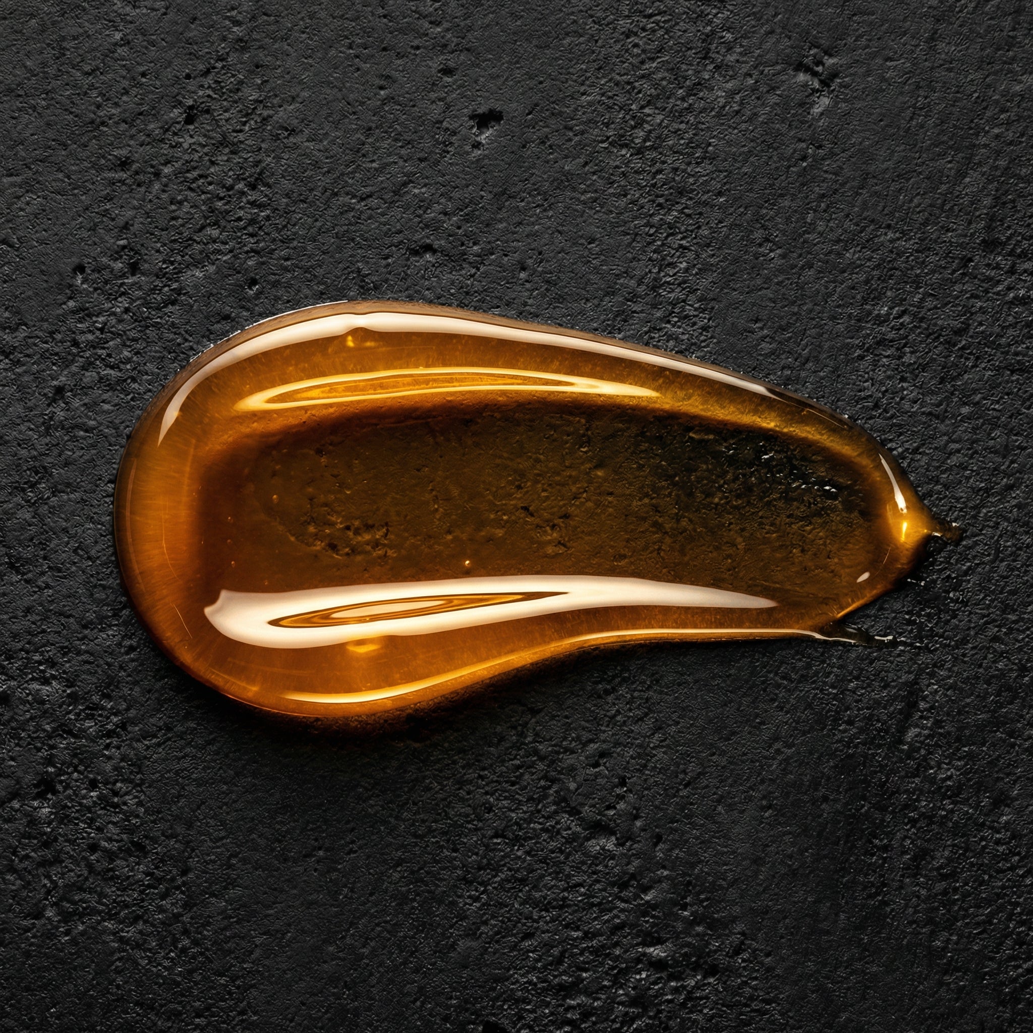 Amber gel texture swatch of FORGE Ritual Body Wash on black stone