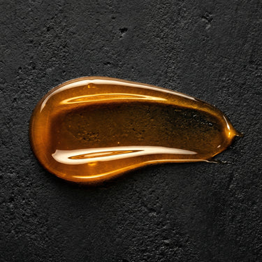 Amber gel texture swatch of FORGE Ritual Body Wash on black stone