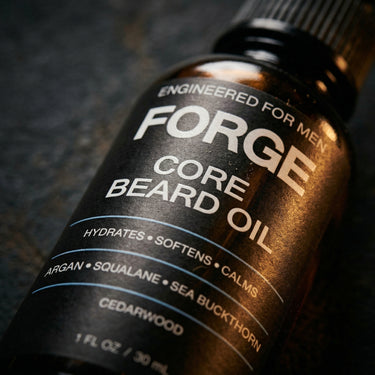 Close-up of the FORGE Core Beard Oil label on dark slate