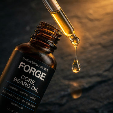 Macro shot of golden FORGE Core Beard Oil dripping from a glass dropper