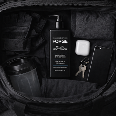 FORGE Ritual Body Wash in an open black tactical gym bag with gloves, shaker, earbuds, keys and phone