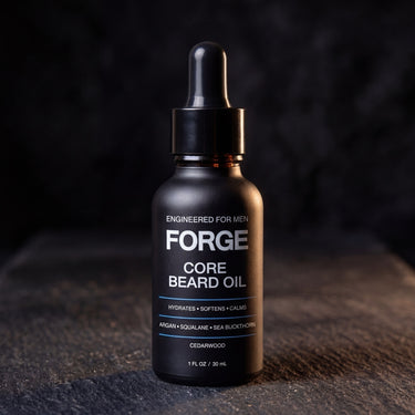 FORGE Core Beard Oil dropper bottle on dark slate lit by warm directional light